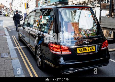 Un direttore funebre cammina di fronte a Un Black Hearse, High Street, Lewes, East Sussex, Regno Unito. Foto Stock