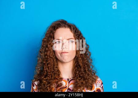 Ritratto fotografico di una giovane donna attraente aspetto scettico spazio vuoto vestiti eleganti e colorati vestiti isolati su sfondo di colore blu Foto Stock