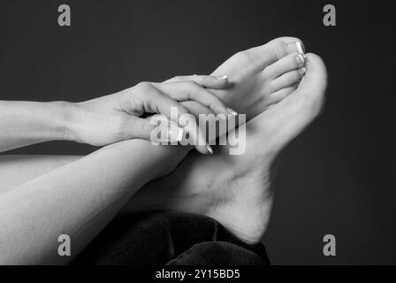 Primo piano di una donna caucasica che sfrega i piedi, simboleggia un massaggio rilassante o sollievo per i piedi stanchi. STATI UNITI. Foto Stock