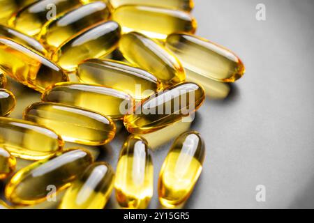 Integratori Omega 3 in capsule softgel naturali traslucide dorate per energia e benessere su una piastra in ceramica grigia. Scatto macro Foto Stock