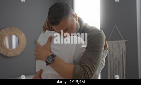 Uomo che conforta donna con abbraccio nel soggiorno mostrando sostegno e amore in un ambiente domestico Foto Stock