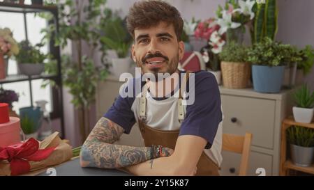 Bell'ispanico con barba e tatuaggi sorridente all'interno di un negozio di fiori. Foto Stock