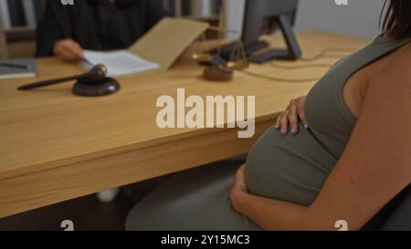 Donna incinta e giudice in carica che discute questioni legali con documenti legali, martelletto e bilancia sulla scrivania Foto Stock