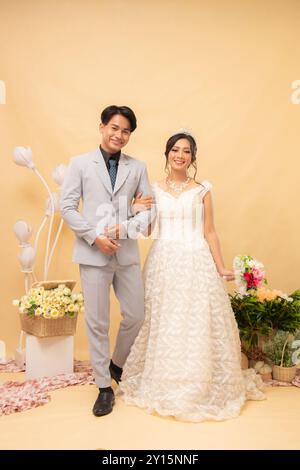 la coppia maschile e femminile che cammina posa sorridendo l'un l'altro di fronte a un intimo scatto fotografico al coperto. studio nazionale di sposa per matrimoni di coppia Foto Stock