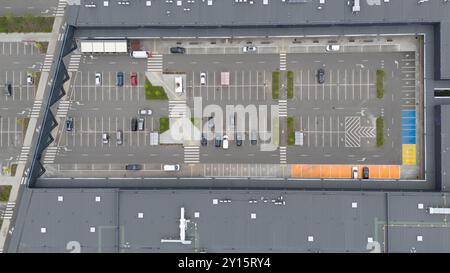 Vista aerea di un ampio parcheggio con varie auto parcheggiate. Il parcheggio dispone di parcheggi segnalati, attraversamenti pedonali e sezioni colorate su On Foto Stock