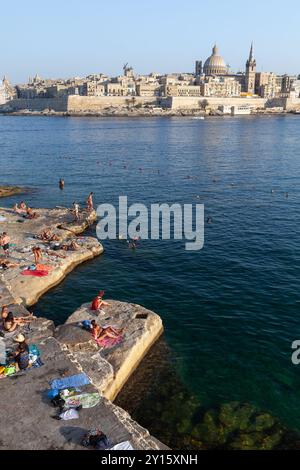 La Valletta, Malta - 23 agosto 2019: Le persone riposano sulla costa la sera. Foto verticale della città vecchia di la Valletta Foto Stock