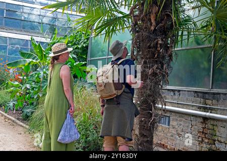 Due persone esaminano la corteccia su palme tropicali presso le piante di vetro in estate presso l'Oxford Botanic Botanical Garden Oxfordshire Inghilterra Regno Unito KATHY DEWITT Foto Stock