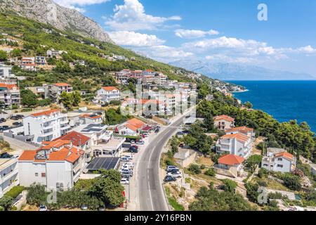 Il villaggio di Stanici con la strada principale lungo la costa accanto alla città di Omis in Croazia Foto Stock