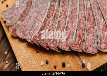 Primo piano di salame salato a fette a bordo, ideale per piatti gourmet e presentazioni di salumi Foto Stock