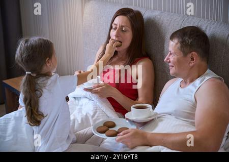 La figlia nutre i biscotti materni in camera da letto Foto Stock