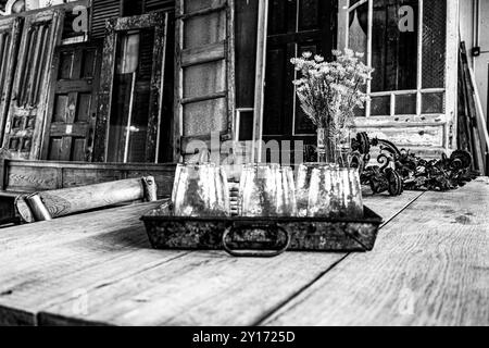 Primo piano di tazze di vetro in vassoio di latta su un tavolo di fattoria in stile "Distressed" con lo sfondo di porte in legno al Farmhouse Style Store Foto Stock