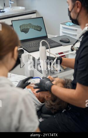 Dentista maschio con assistente che cura i denti di anziana signora Foto Stock