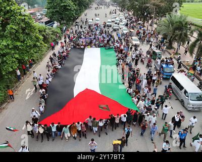 Dhaka, Wari, Bangladesh. 5 settembre 2024. I manifestanti inondano la bandiera nazionale del Bangladesh durante la marcia dei martiri, una manifestazione organizzata dagli studenti contro la discriminazione per celebrare un mese per l'estromissione dell'ex primo ministro Sheikh Hasina, a Dacca il 5 settembre 2024. L'ex Premier del Bangladesh Sheikh Hasina dovrebbe "tacere" mentre era in esilio in India fino a quando non viene portata a casa per il processo, il leader ad interim Muhammad Yunus ha detto ai media indiani il 5 settembre. Hasina, 76 anni, fuggì in India in elicottero un mese fa mentre i manifestanti marciavano sul suo palazzo in una drammatica fine al suo dominio pugnalato di ferro Foto Stock