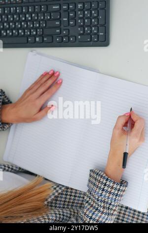Mani femminili che tengono una penna e fanno appunti da vicino. Copia spazio Foto Stock