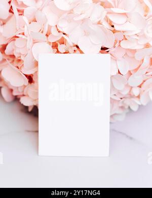 Scheda di carta bianca mockup su sfondo rosa ortensie. Modello biglietto da visita, biglietto da visita, biglietto da visita, vista frontale. Modello di progettazione Foto Stock