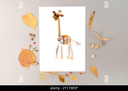 Delizioso artigianato naturalistico autunnale per bambini, con una giraffa fatta di foglie. Corpo e collo realizzati in foglia, foglie più piccole formano la testa, foglie gialle Foto Stock