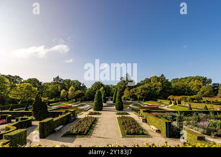 Paesaggio panoramico dei giardini del Castello di Arcen, fontana, fiori, sentieri pedonali e verdi alberi frondoso sullo sfondo blu, giornata di sole a li Foto Stock