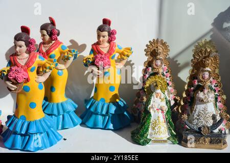 Una vivace mostra di souvenir tradizionali spagnoli con statuette di ballerini di flamenco e icone religiose in una vetrina di Siviglia, che cattura l'ess Foto Stock