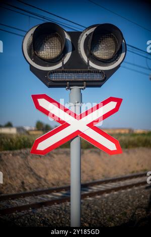 Immagine ravvicinata di un segnale di attraversamento ferroviario, che simboleggia la prudenza e la sicurezza in un incrocio ferroviario soleggiato. Foto Stock