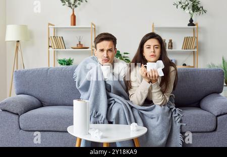 Sick famiglia coppia che soffre di malattia a casa su divano Foto Stock
