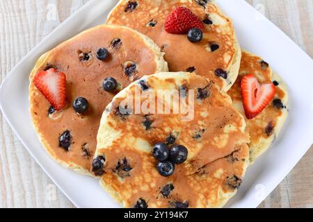 Vista dall'alto di un piatto pieno di pancake freschi fatti in casa con mirtilli e fragole. Foto Stock