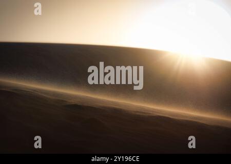 Il sole tramonta mentre i forti venti soffiano sabbia sulle dune del White Sands National Park vicino ad Alamogordo, New Mexico. Foto Stock