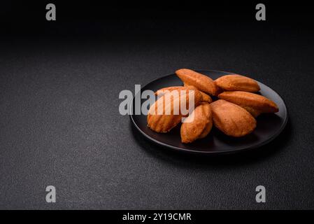 Tradizionali biscotti francesi madeleine con sapore di nocciola su sfondo di cemento scuro Foto Stock