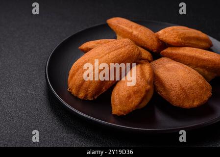 Tradizionali biscotti francesi madeleine con sapore di nocciola su sfondo di cemento scuro Foto Stock