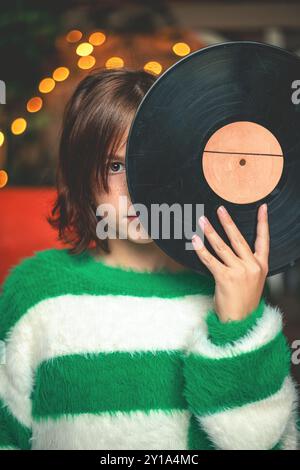 Tenera ragazza con un disco in vinile retrò davanti al viso, con spazio per le copie per il testo Foto Stock