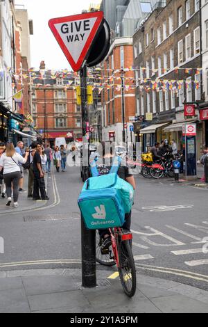 Un corriere Deliveroo in attesa su Old Compton Street, Soho, Londra, Regno Unito. 30 agosto 2024 Foto Stock