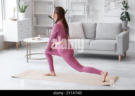 Giovane donna con dreadlock che fa yoga a casa Foto Stock