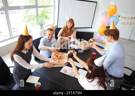 Gruppo di uomini d'affari che mangiano pizza alla festa di compleanno in ufficio Foto Stock