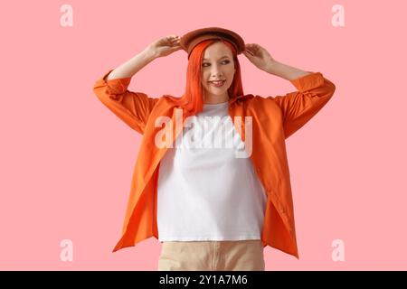 Bella giovane donna felice in berretto su sfondo rosa Foto Stock