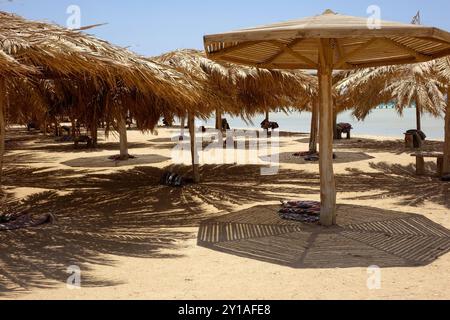 Il sole filtra attraverso gli ombrelloni di Paradise Island a Hurghada, invitante relax su una spiaggia sabbiosa. I visitatori apprezzano la calda atmosfera Foto Stock