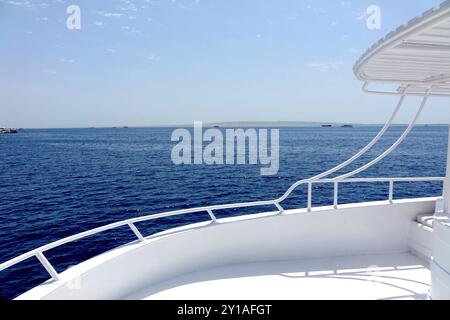 Una vista tranquilla da uno yacht mostra le profonde acque blu del Mar Rosso, punteggiate da barche lontane e un sereno orizzonte nella località turistica di Hurghada. Foto Stock
