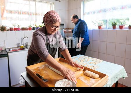 sorridente cucina latina senior e preparare il pasto con suo marito nella loro cucina tradizionale Foto Stock