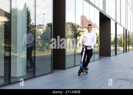 Giovani e casual uomo d affari di equitazione scooter elettrico in città Foto Stock