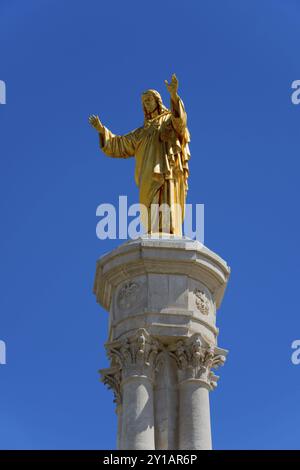 Statua dorata di Gesù su un'alta colonna di fronte a un cielo blu, statua di Cristo, Santuario de Fatima, luogo di pellegrinaggio, Fatima, Fatima, Ourem, Babbo Natale Foto Stock