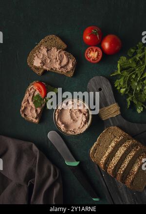 Patè di carne di fegato spalmato su pane di segale, colazione, primo piano, sfondo scuro. niente persone, concentrazione selettiva Foto Stock