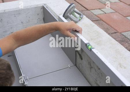 Piastrellista lavora su un nuovo ingresso di casa, tuttofare locale e professionale che applica piastrelle ai gradini Foto Stock