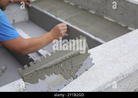 Piastrellista lavora su un nuovo ingresso di casa, tuttofare locale e professionale che applica piastrelle ai gradini Foto Stock