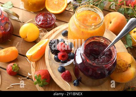 Marmellate naturali fatte in casa di vari tipi di frutta in vasetti su un tavolo di legno in campagna. Vista rialzata. Foto Stock
