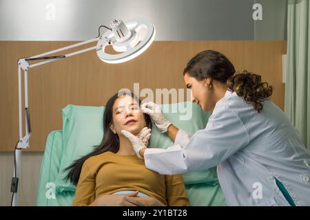 Medico o dermatologo che esamina la pelle del viso di un giovane paziente prepararsi prima di un intervento di lifting. Atmosfera presso il reparto di chirurgia estetica in h Foto Stock