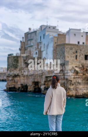 Retrovisione di una donna che guarda al villaggio italiano di Polignano a Mare Foto Stock