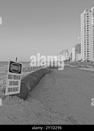 Segnale di pericolo di pericolo vicino alla conduttura di dragaggio in un progetto di restauro della spiaggia a Myrtle Beach, South Carolina, Stati Uniti. Foto Stock