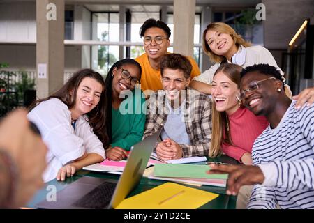 Gruppo di giovani studenti diversi che si presentano allegri per scattare foto nella caffetteria del campus universitario. Foto Stock