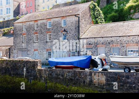 Una piccola barca si trova di fronte ad un vecchio edificio nel Porto di Tenby. Foto Stock