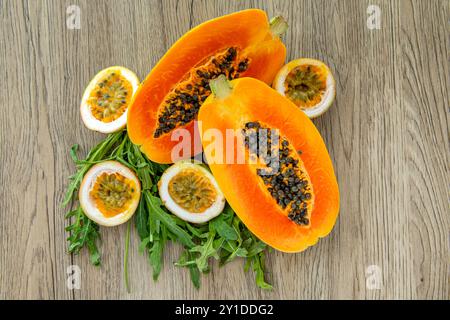 Papaya, frutto della passione e rucola su un leggero sfondo di legno. Fette di papaya dolce e maracuja su fondo di legno, papaya tagliate a metà, copia Foto Stock