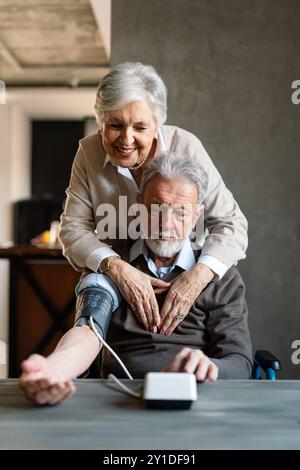 La coppia di anziani misura la pressione sanguigna l'un l'altro. Concetto di controllo dello stato di salute a casa Foto Stock
