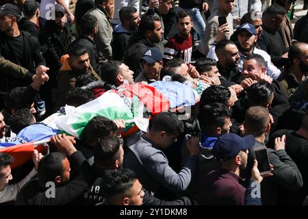 Nablus, Palestina, 20 marzo 2019. I lutti trasportano i corpi di Zaid Nuri, 20 anni, e Raed Hamdan, 21 anni, due uomini palestinesi uccisi dal fuoco vivo delle forze israeliane all'inizio di mercoledì nella zona di al-Ghawi, mentre le truppe israeliane scortavano centinaia di coloni a visitare la tomba di Giuseppe nella città di Nablus nella sponda occidentale settentrionale. Mentre le forze israeliane scortavano il convoglio di autobus di coloni ebrei nel sito, situato nell'area controllata dai palestinesi, i soldati israeliani aprirono il fuoco verso un veicolo in cui Hamdan e Nuri viaggiavano uccidendoli. L'esercito israeliano ha affermato che i due palestinesi presumibilmente Foto Stock